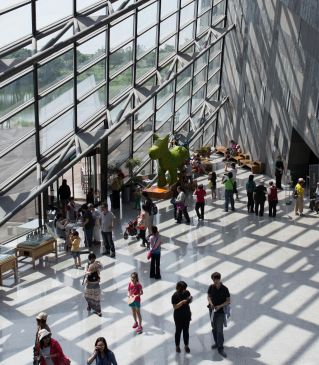 A modern interior lobby with people gathered near large glass windows.