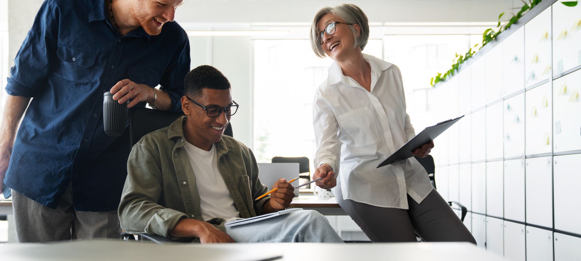 A diverse group of coworkers in a modern office engaged in teamwork using technology.